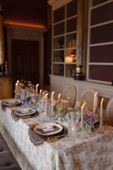 Long reception table styled with candles and wildflower arrangements inside a historic library
