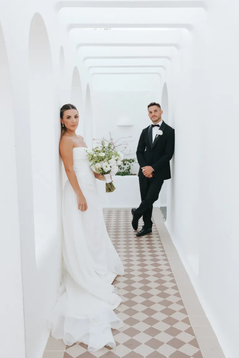 The couple pose apart in Casa Arte’s bright arched corridor with patterned floor tiles.