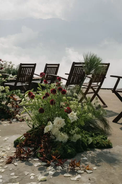 Wooden ceremony chairs and wild floral arrangements facing out toward the clouds.
