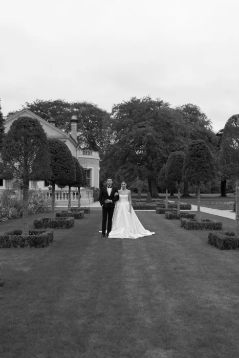 Bride and groom standing together in the formal gardens of a country house wedding venue