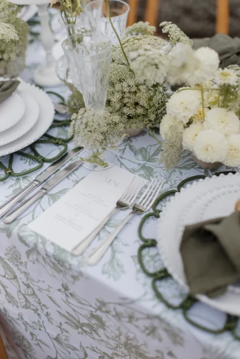 Close-up of botanical wedding table styling with floral arrangements, menus and crystal glassware