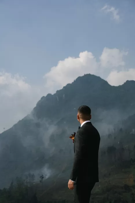 The groom looks toward mist-covered mountains before the ceremony.