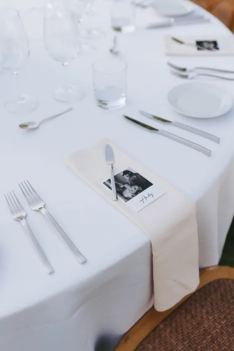 A personalised photo place card rests on a white linen table setting.