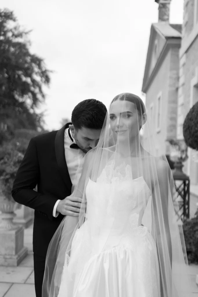 Black and white portrait of the couple beneath the bride's veil.