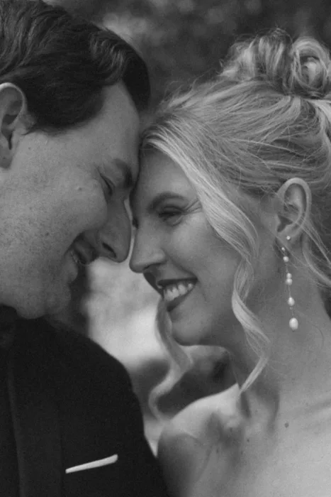 Black and white close-up of the couple smiling together in an intimate portrait.