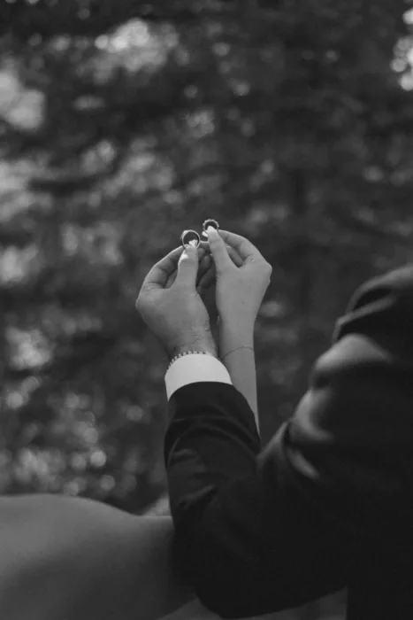 Black and white close-up of the couple holding their wedding rings together.