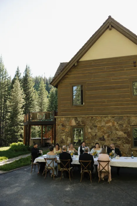 Small wedding dinner set outside a timber lodge, surrounded by pine trees.